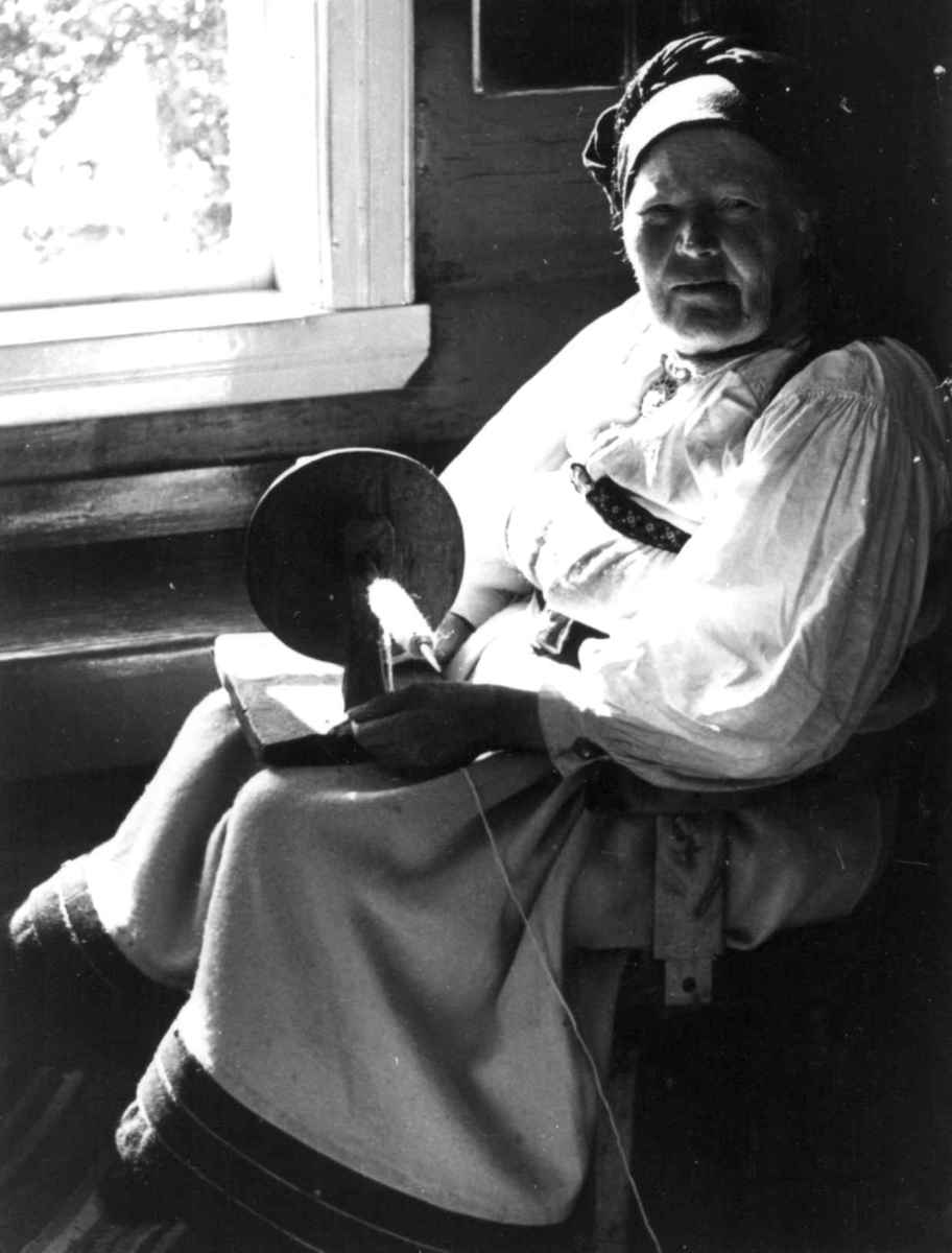 Valle 1939. Portrett av Gunnhild Viki mens hun spoler garn på trespole.