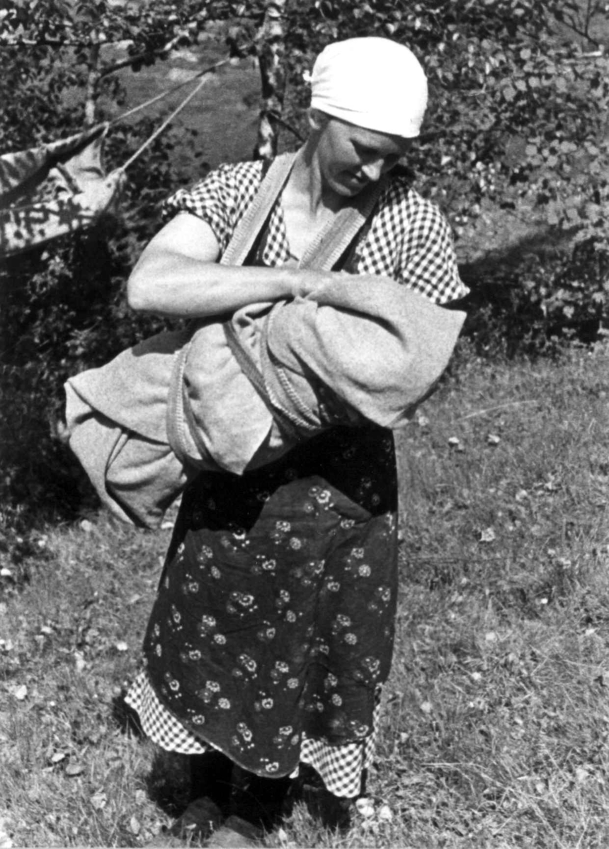 Ingeborg bærer et barn i linde på Engedal. Fjotland, Kvinesdal 1941.