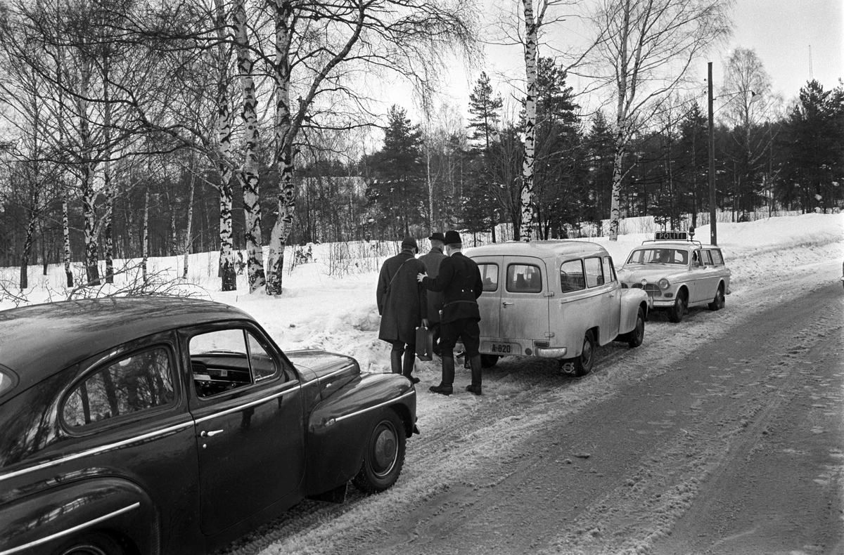 Politietterforskere på åstedsbefaring. Politiet ettersøker en voldsforbryter i skogsområdet rundt Brannfjell i februar 1961. Politibilen til høyre er  Volvo Amazon stasjonsvogn. Politibilen til venstre er en Volvo PV.
