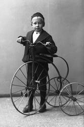 Portrett, gutt på en trehjulsykkel, ca 1892. Kristen Thrue.