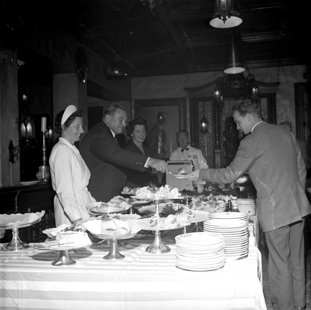 Karl Johans gate 41b, Oslo, 13.10.1960. Restaurant Blom. Tre menn i samtale. Mat på stettefat.