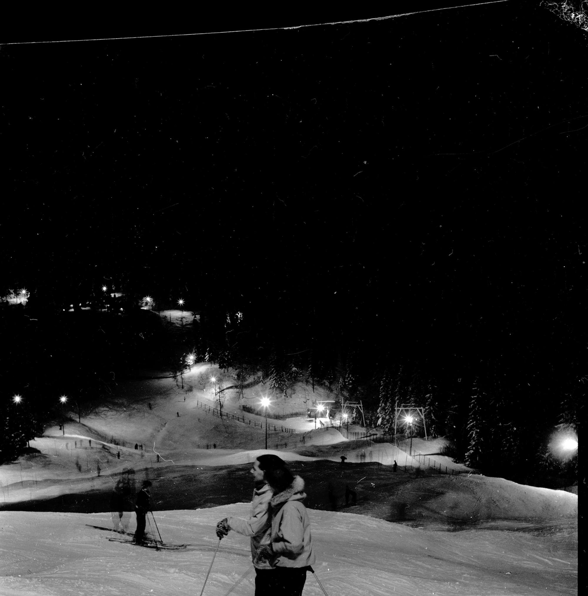 Nordmarka, Oslo, 12.02.1955. Lysløypa. Skiløpere i skogen.