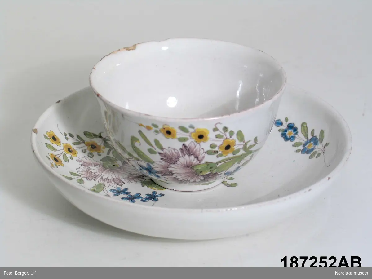 Montertext i Dukade bord:
Kaffekopp med fat av fajans med målad blomdekor. 1700-talets mitt. Möjligen nordtysk tillverkning. 

