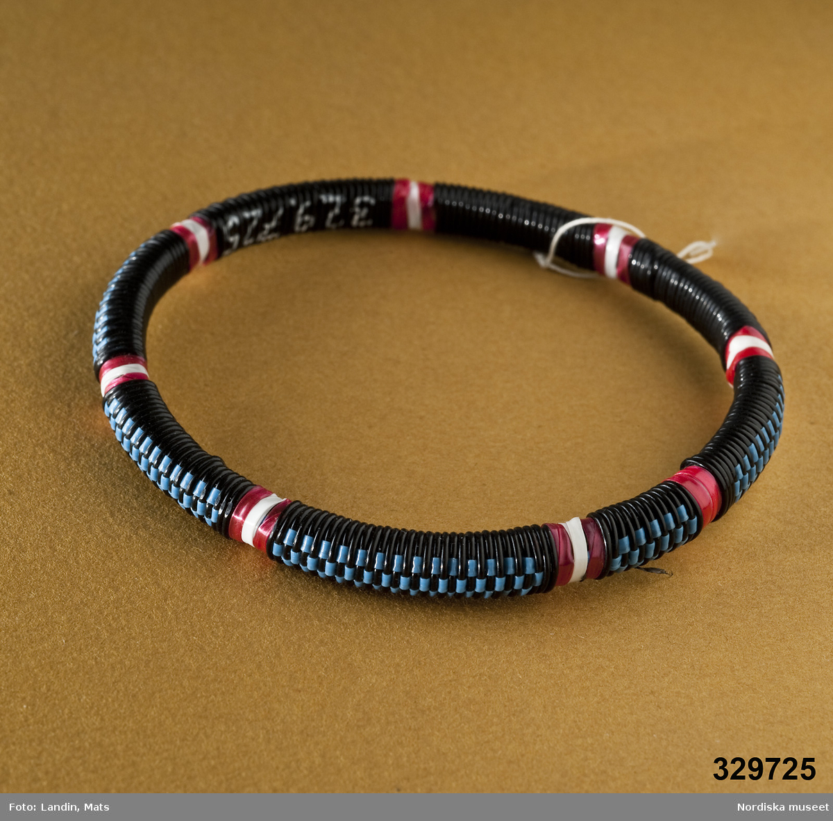 Runt armband med mönster vävt av tunna plastband. Afrikanska influenser.
/Zingoalla Rosenqvist 2009-02-05