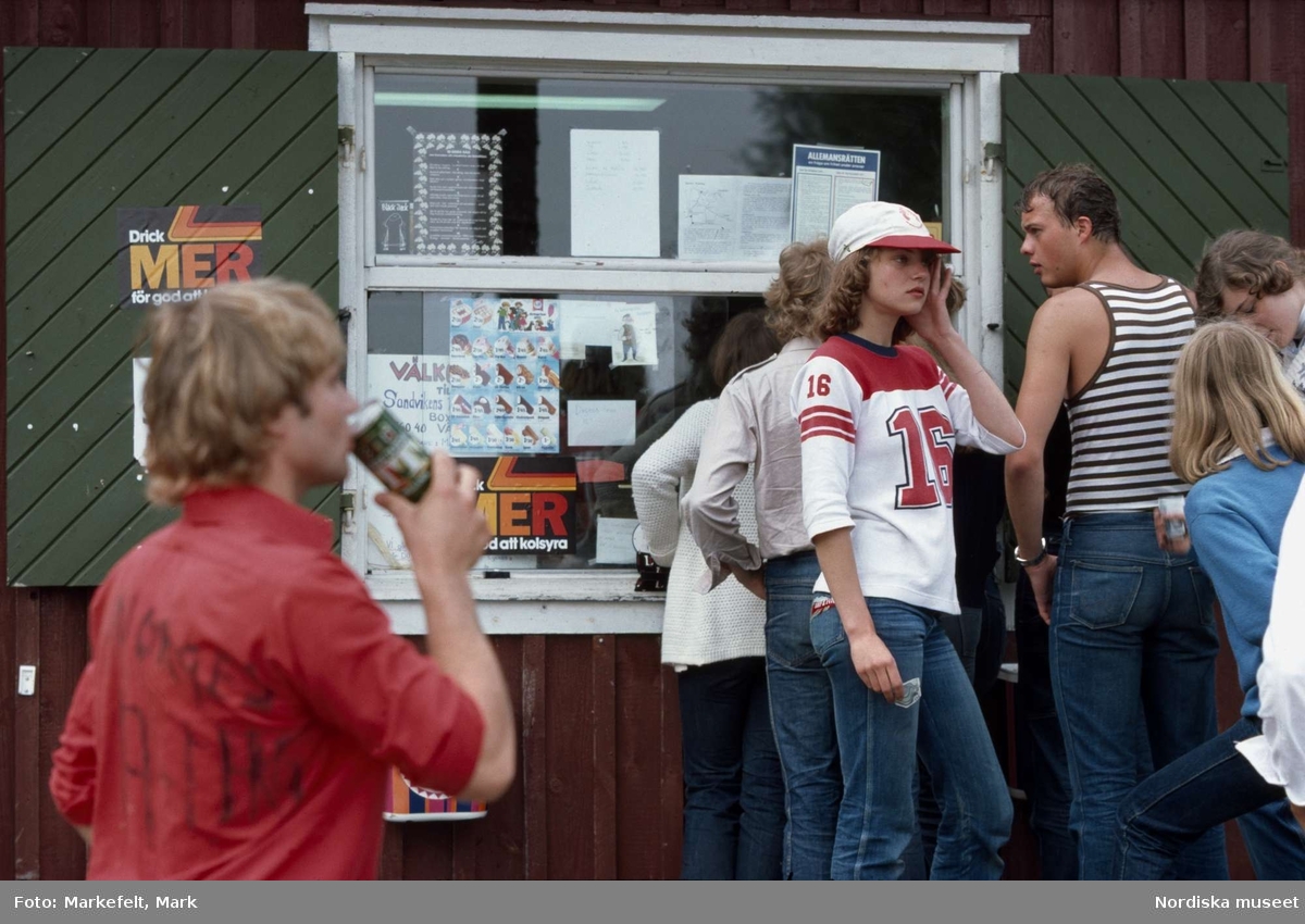 Ungdomar. Kiosk vid Sandvikens campingplats, Väddö. Några ungdomar i jeans står och hänger utanför kiosken. 