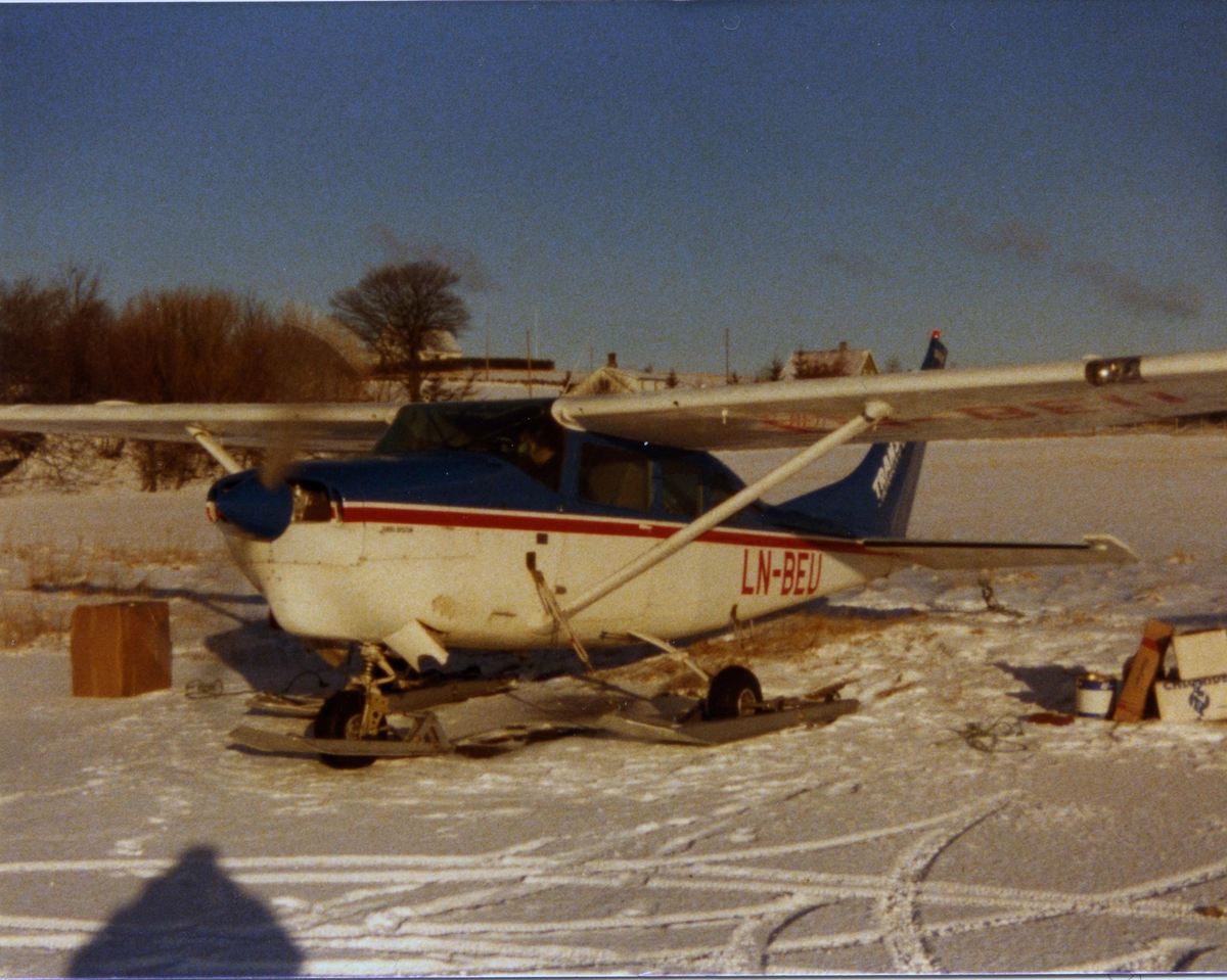 Lufthavn (flyplass). Ett fly, LN-BEU, Cessna 206, fra Bergen Ait Transport, Utstyrt med hjul og ski. Snødekke.