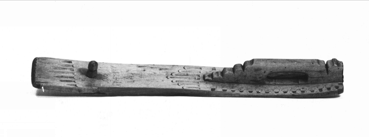 Mangelbräde. Handtag i samma stycke som brädan. Itappad plugg. Skärningar; staplar bildande pyramid. Inristat: ANO 1747.