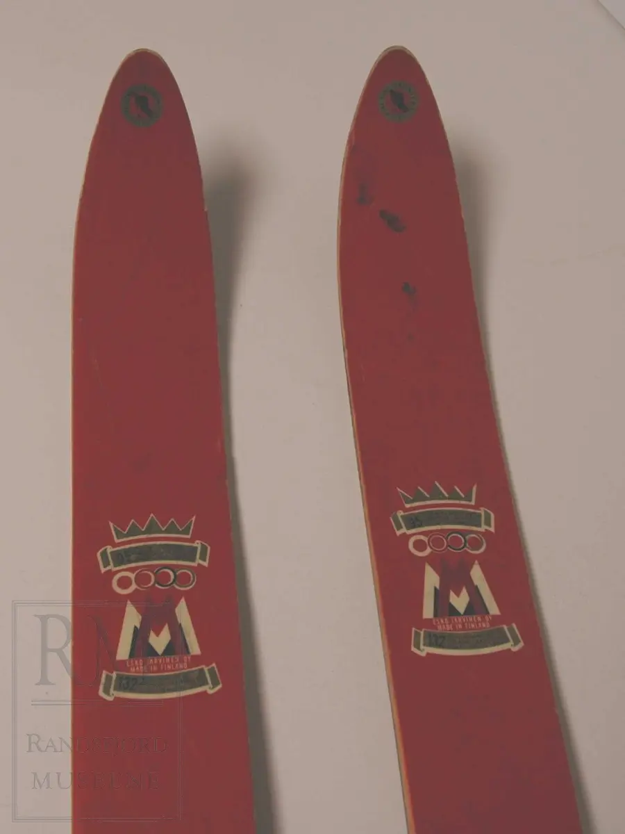 Røde ski med blå kalosjebindinger i lær
