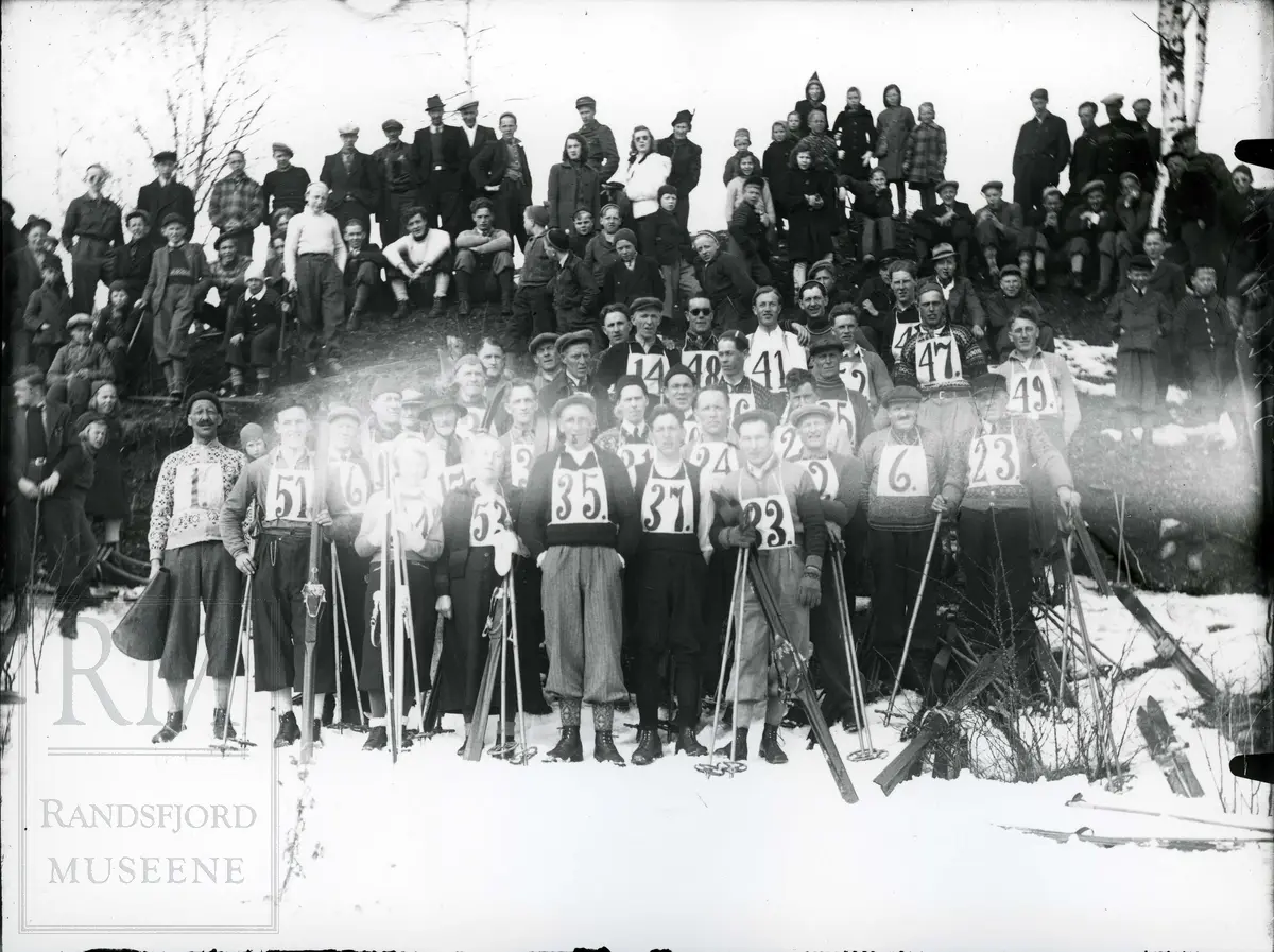 Deltakere i skirenn med ski, staver og startnummer samt publikum oppstilt i gruppe