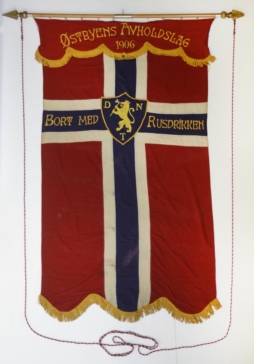 Forside: Riksvåpenet med bokstavene DNT på blått skjold med gul kant rundt plassert midt i det norske flaggets kors. Tekst på begge sider.