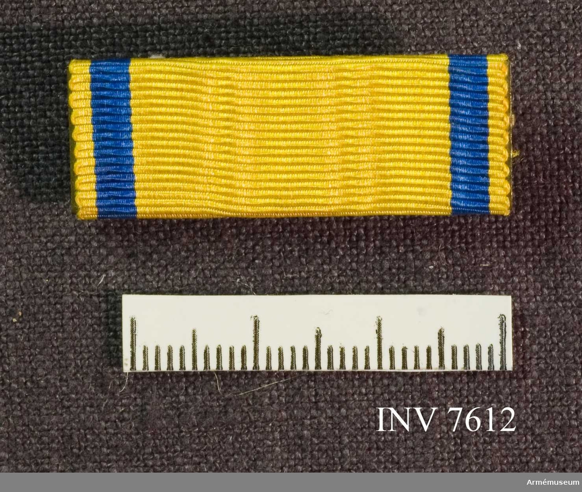 Metallspänne överklätt med samma band vad gäller färg och bredd som svärdstecknets band.

Förvaras tillsammans med AM 7611 i röd ask med gulddekor.