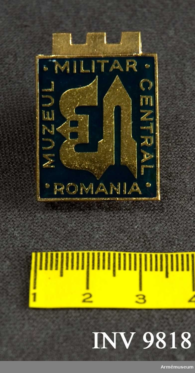 Märke från Muzeul Militar Central Romania. Ett metaIlmärke som kan fästas på plagget med en nålhake. Framsidan är i blå emalj med en stiliserad dekor i guld med omskrift i guld enligt följande:MUZEUL MILITAR CENTRAL ROMANIA. Märket förvaras i plakettasken.