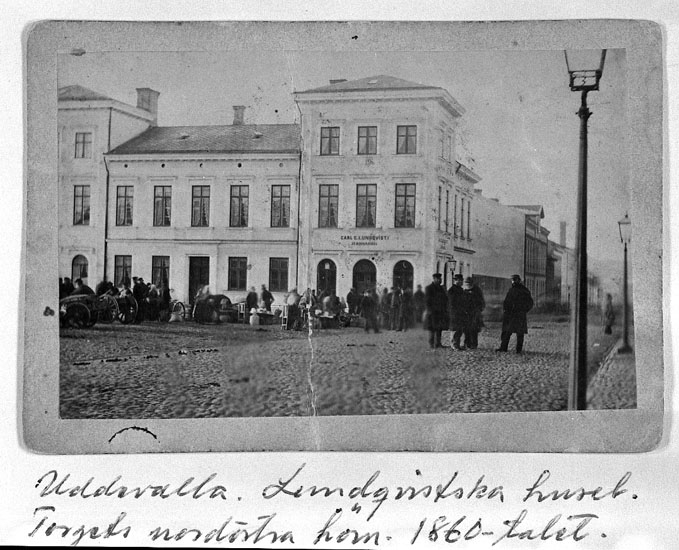 Text på kortet: "Uddevalla. Lundqvistska huset. Torgets nordöstra hörn. 1860-talet".

Enligt tidigare noteringar: "Lundqvistska huset, Torgets nordöstra hörn. 1860-talet. 
Repro 1984 av foto".
