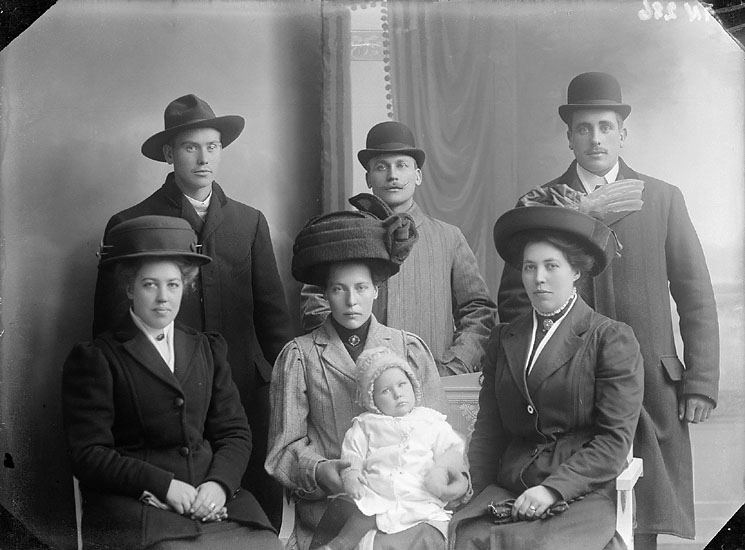 Enligt senare noteringar: "Ateljéfoto av tre män, tre kvinnor och ett litet barn. 
Samtliga i ytterkläder och huvudbonader, kvinnorna med handskar."