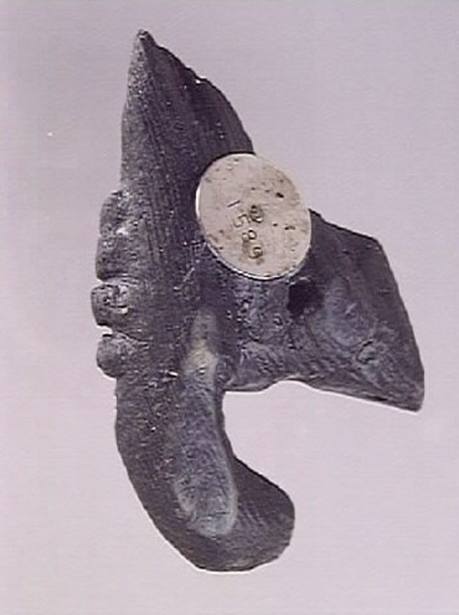 Del av skulptur, högerhand hållande ett horn eller liknande. Handen är bruten, liksom hornets bägge ändar. Fyrkantigt hål genom handen.

Skulpturdelen är relativt välbevarad.