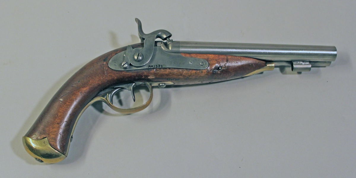 Slaglåspistol, dubbelpipig kal. 14, av
KungligaGeneralpoststyrelsens modell från år 1853 (skr. 18540323).
Pistolenhar dubbla pipor hopfogade med en spång på översidan.
Pipornas längd190 mm. Svansskruvar med krok och separat svansjärn.
Låsblecken heltinställda i stocken, försedda med varhackar. Endast en
låsskruv somgår från vänster låsbleck. Halvstock av björk med
mässingbeslag.Kolvkappan med två spetsiga flikar. Laddstock av trä
med hornända.Kolvkappa (numrerad 5) ej tillhörande, vänster varhake
avbruten.