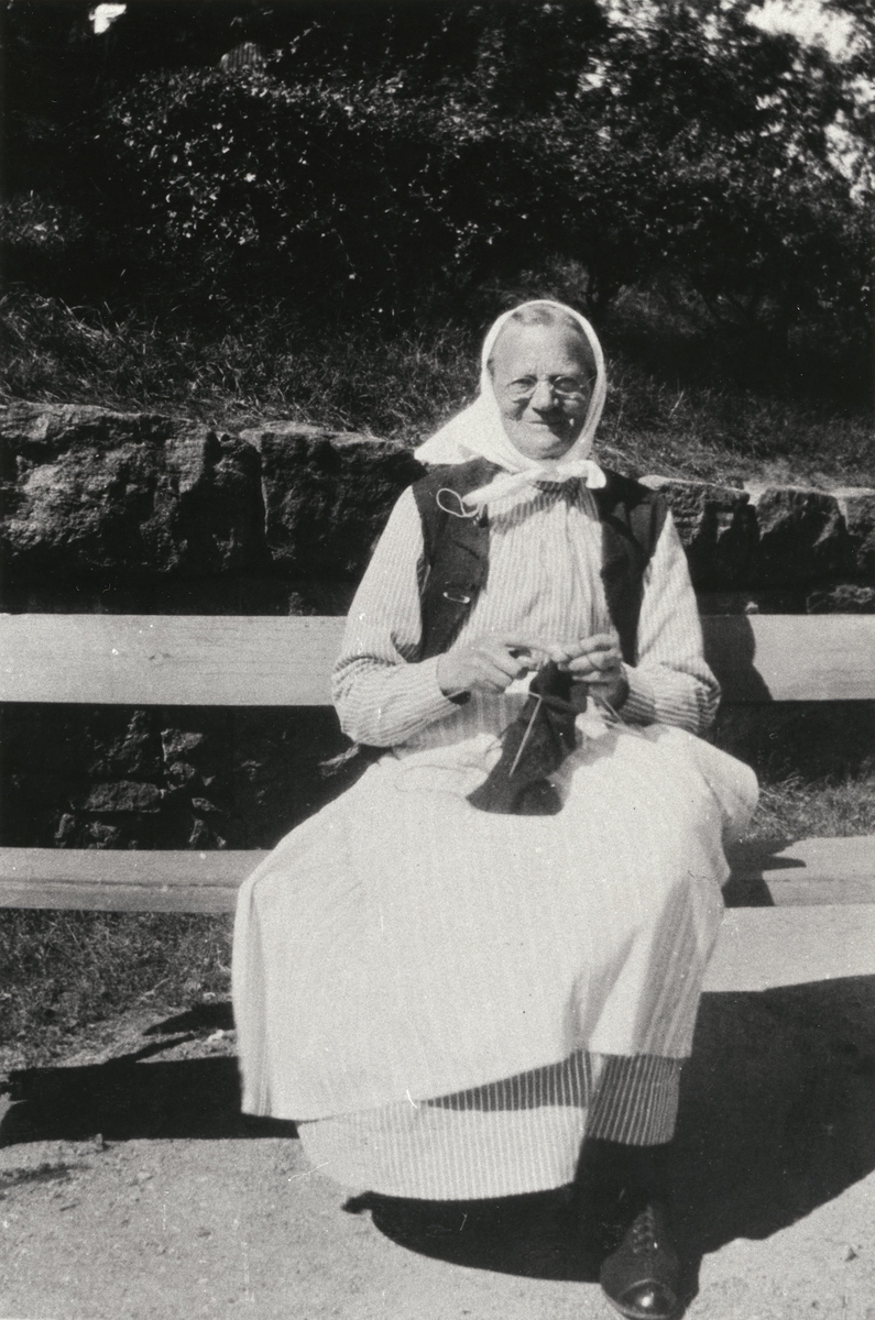Äldre kvinna som sitter på en bänk vid Kärra Hökegård, ett försörjningshem för såväl senildementa som psykiskt sjuka, utvecklingsstörda och ensamstående mödrar. Verksamheten försvann i och med att Lackarebäckshemmet stod klart 1951.