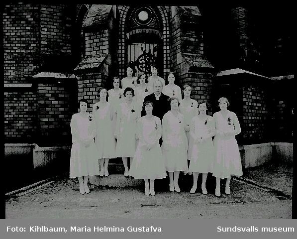 Grupporträtt framför Gustav Adolfs kyrka. Konfirmation, flickor och präst.