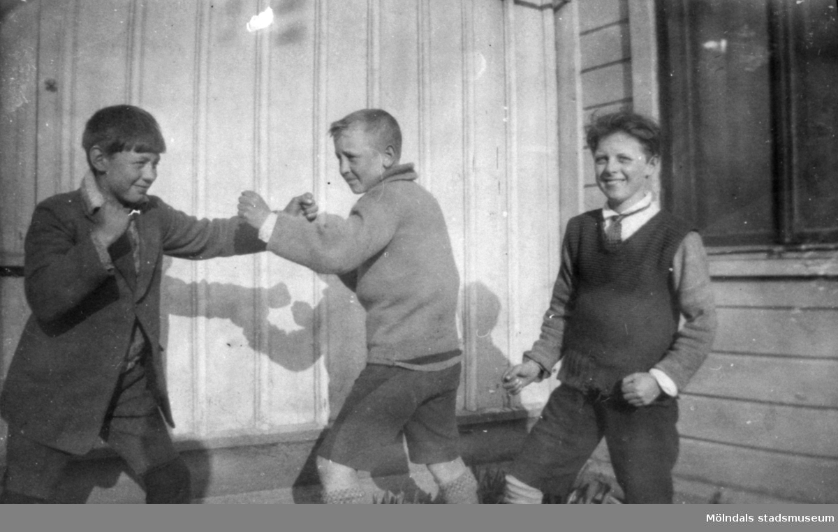 Två killar som låtsas-bråkar och en ung Helmer Garthman längst till höger. 1920-tal.