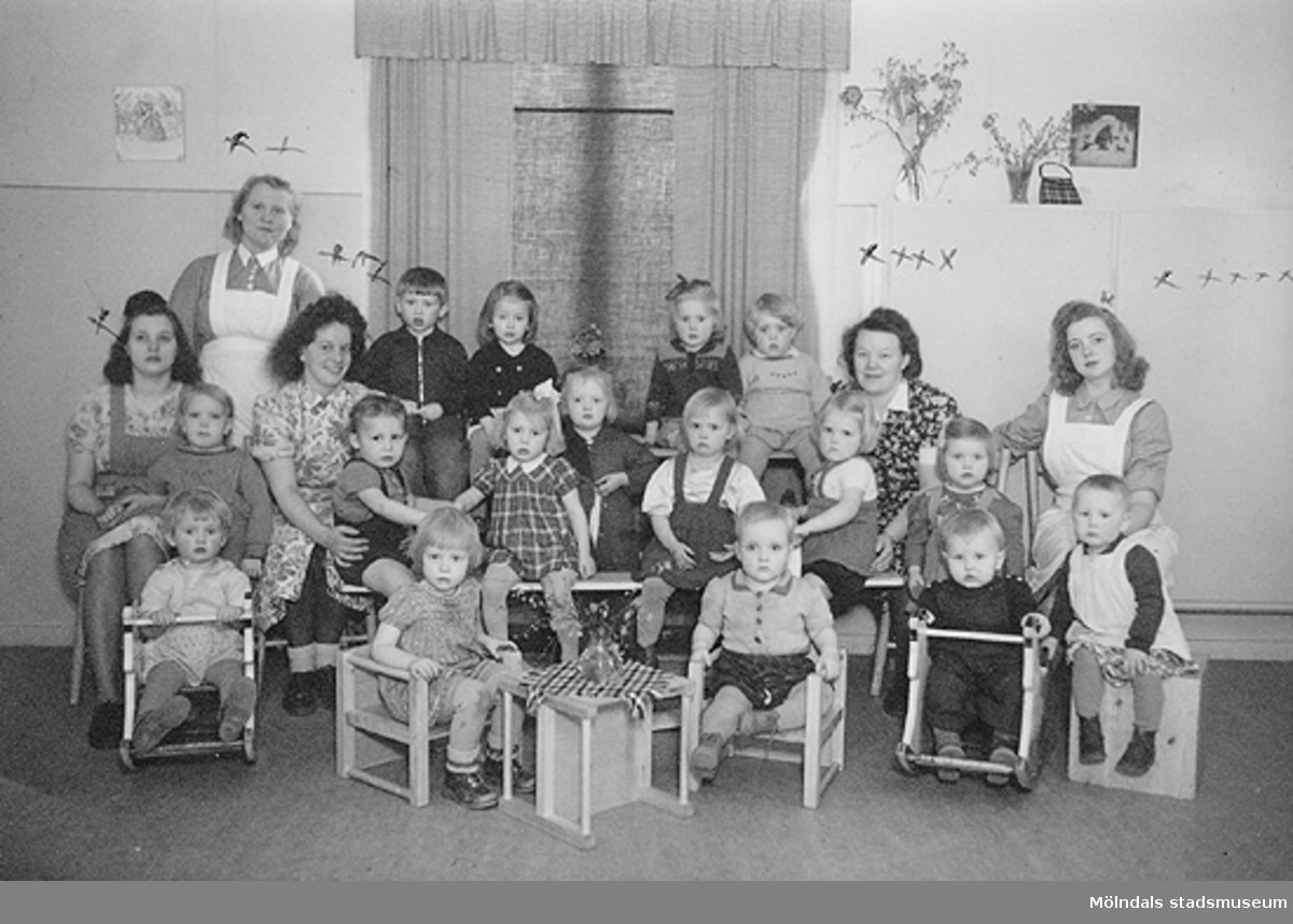 Gruppfoto av barn med förskollärare och praktikanter, bl.a "praktikant" Margit, en praktikant från Norge och ett biträde anställt från Mölnlycke Fabriker.
Kortet sitter i Margit Wannerbergs fotoalbum.