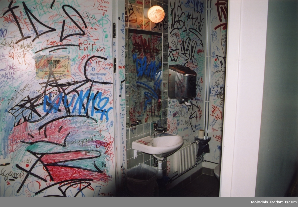 Graffitimålad toalett i samband med utställningen "Alltså finns jag" på Mölndals museum, år 2003. Museet hade lagt tuschpennor som besökarna fick använda till att rita på toaletternas inneväggar och dörrar. Efter utställningens slut återställdes de två toaletterna till ursprungligt skick.