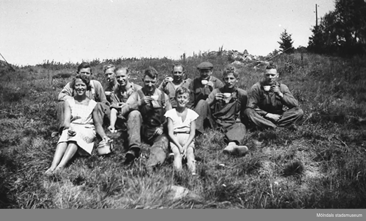 Sommar i Lindome, början av 1940-talet. Berit Gustafsson, några män och en pojke fikar i gröngräset.