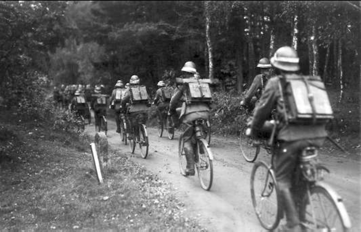 Regementets återkomst från höstmanövern 1934. Förbimarsch för general E Testorp. Signalavdelning, signalmateriel och radiostationer medföres på hästanspänd kärra och på husarens cykel och rygg.