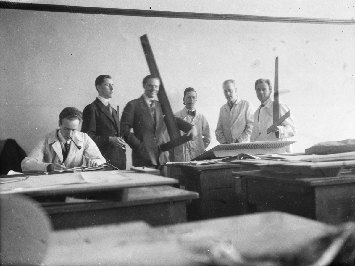 Gruppbild av sex unga män i en ritsal med vinkellinjaler och ritbord.
David Helldén sittande längst till vänster.
Arkitektskola
Interiör
