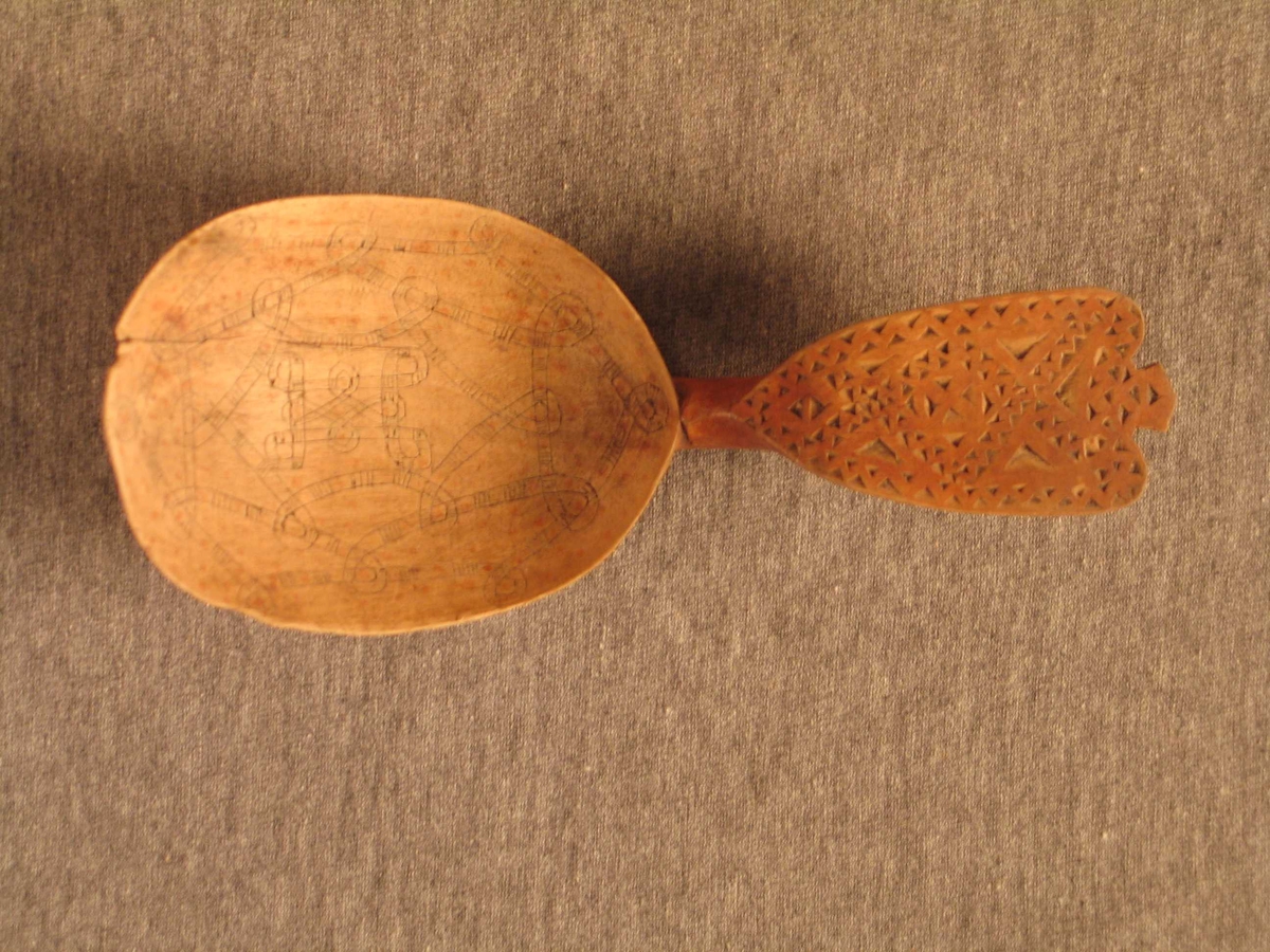 Bandslyng ornament i bladet. Forma som tredobbel utvida valknute. Skeia har karveskrud på skaftet