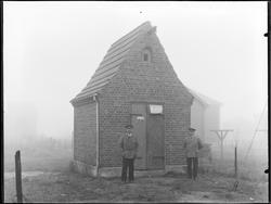 Tune elektrisitetsverk. Transformatorkiosk i tegl, to menn.