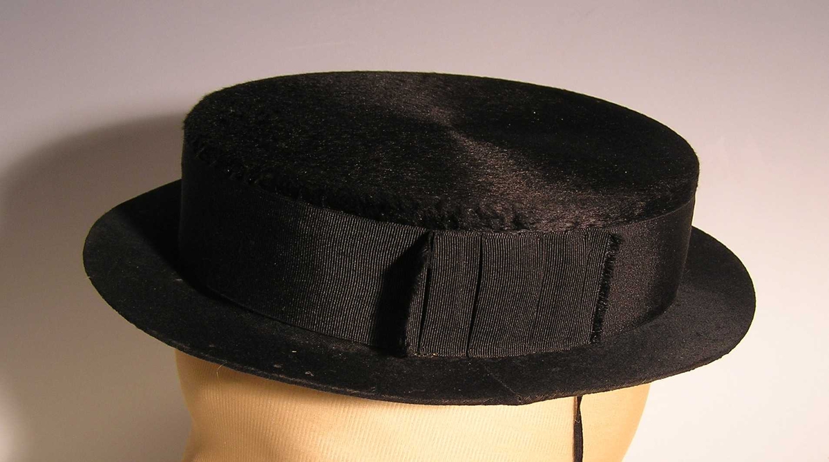 Form: ovalt
Bram: rett, stiv. Lasting brem - bredde 3 cm.
 Floss utvendig,  lasting innvendig. Bredt ripssilkeband festet med knappenål som dekor .Tynn snor festet til linning i hatten.
