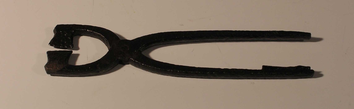 Form: to armer som krysser hverandre; naglet sammen der de krysser; bladene som klipper ser ut som to små økser
