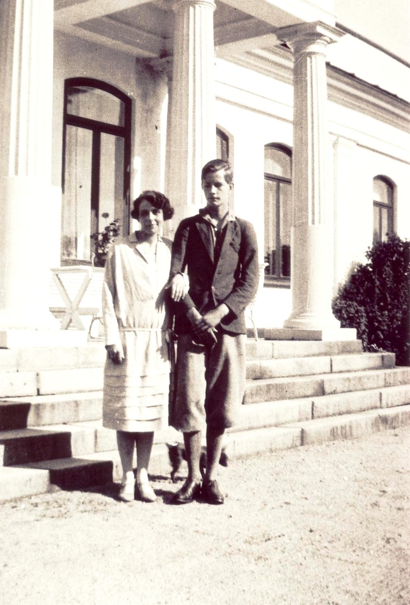 Foto av Eugenie Aall sammen med sin gutt Niels Frederik Aall foran søylene på deres hjem, Ulefos Herregård