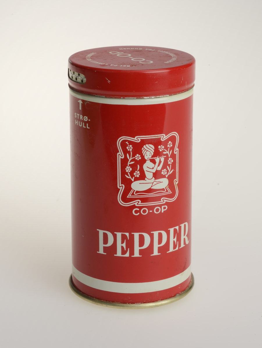 Krydderboks i metall fra Co-op for pepper. Boksen er rød med hvit skrift. Lokket kan skrus for å gi "strøhull" og for å gi "stort hull". Bunnen er avtagbar for påfylling.