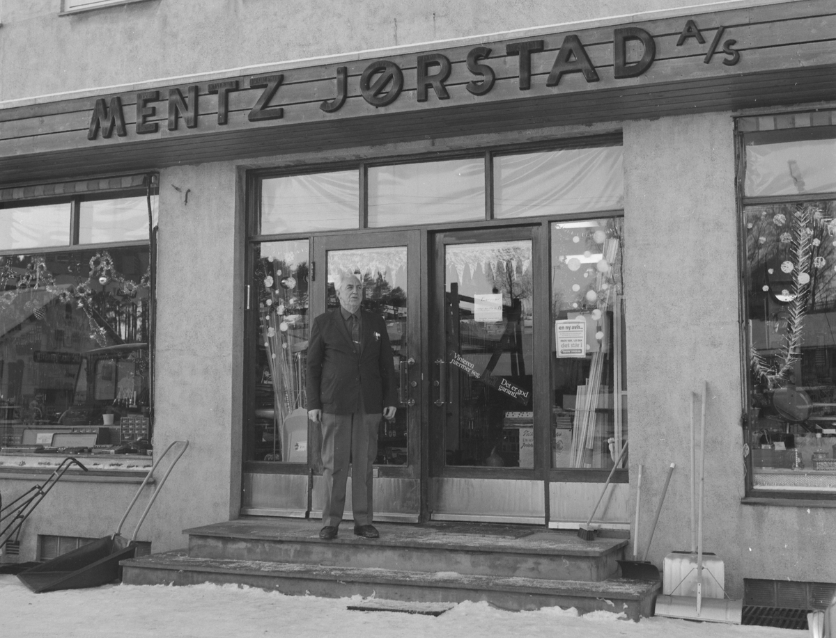 Mentz Jørstad AS, Jern og byggevareforretning i Nygata, Brumunddal. 
Juleutstilling, juletre. Bernhard Bakken utenfor forretningen.