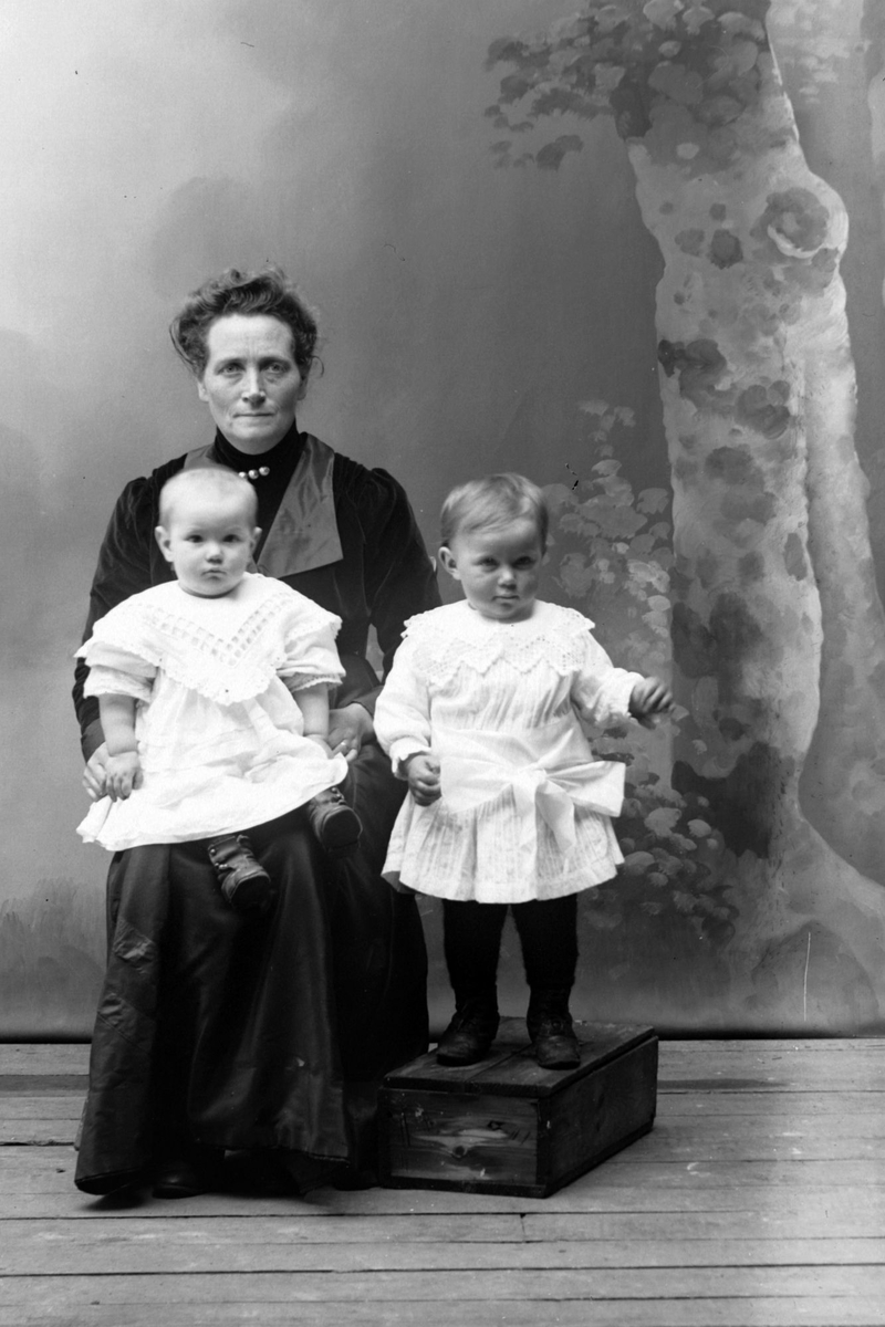 Studioportrett av en kvinne med to barn.