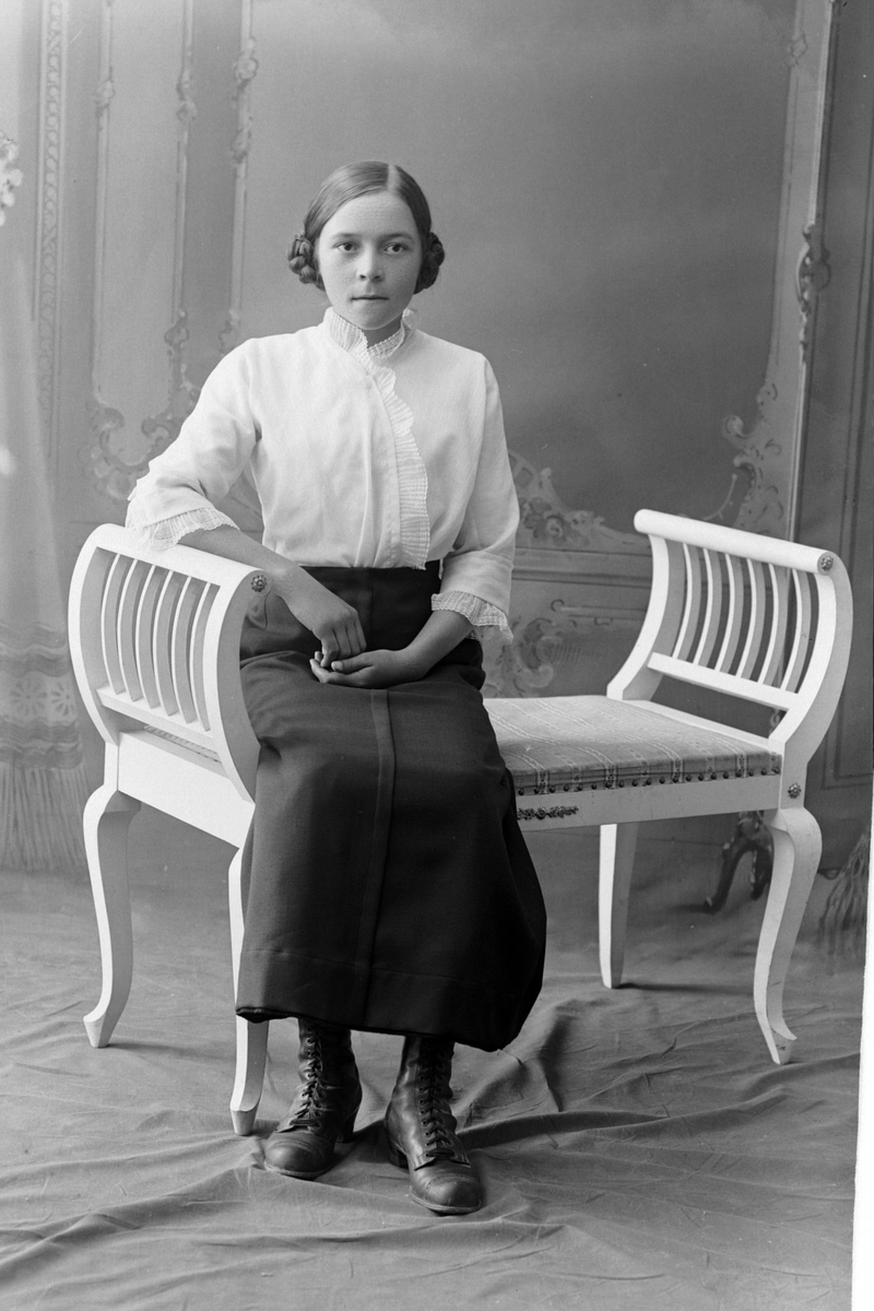 Studioportrett av en kvinne som sitter på en benk.