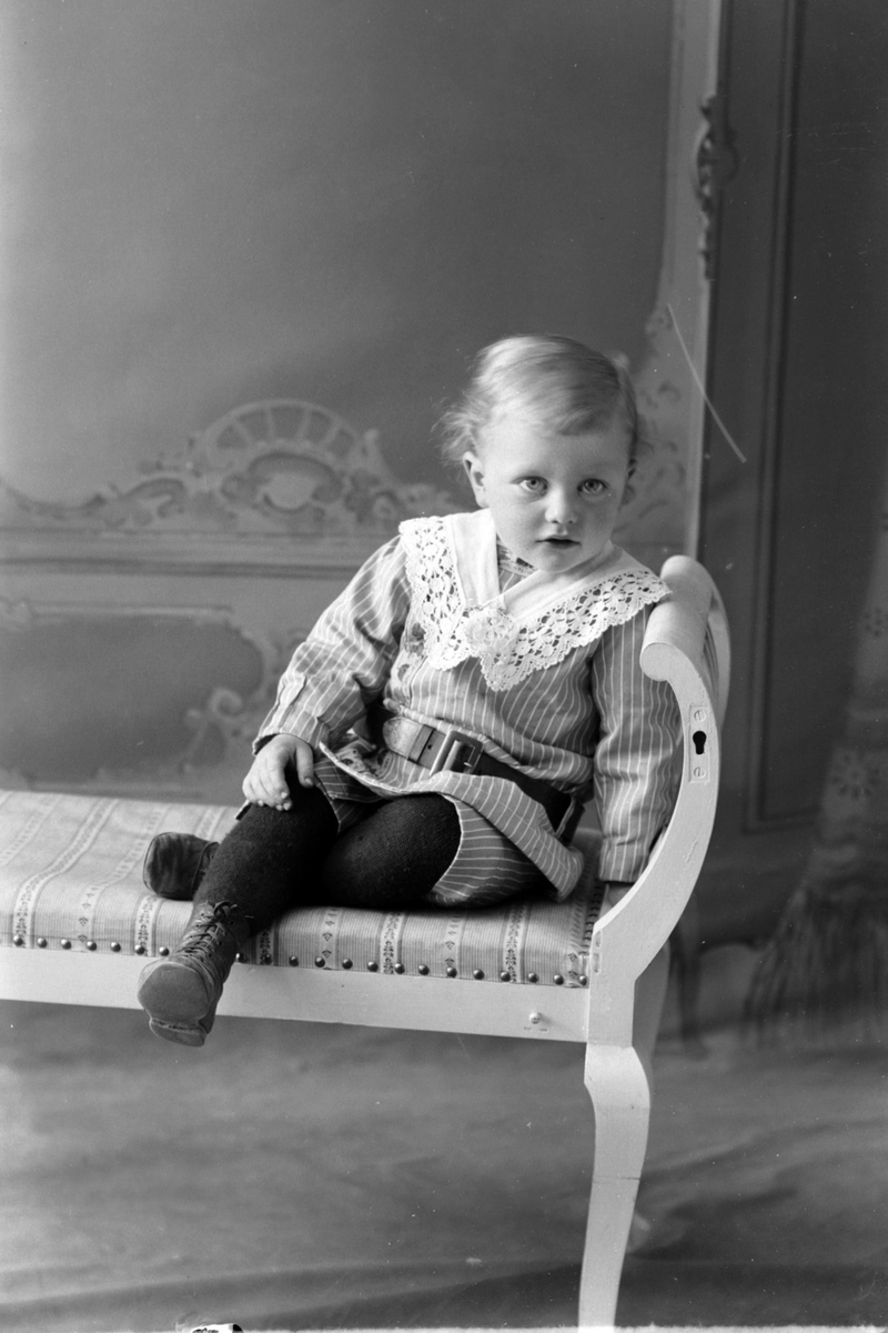 Studioportrett av et barn som sitter på en benk.