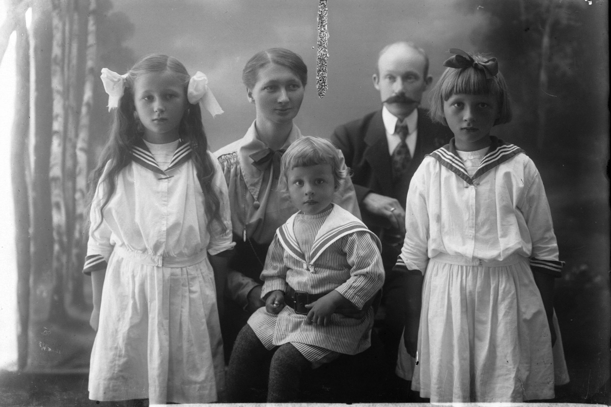 Studioportrett av en mann og kvinne med tre barn kledd i matrosdress.