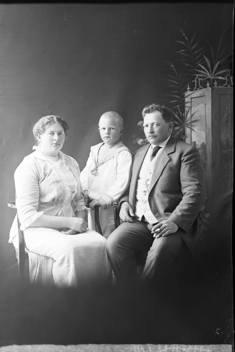 Studioportrett av en mann og kvinne med et barn mellom dem.
