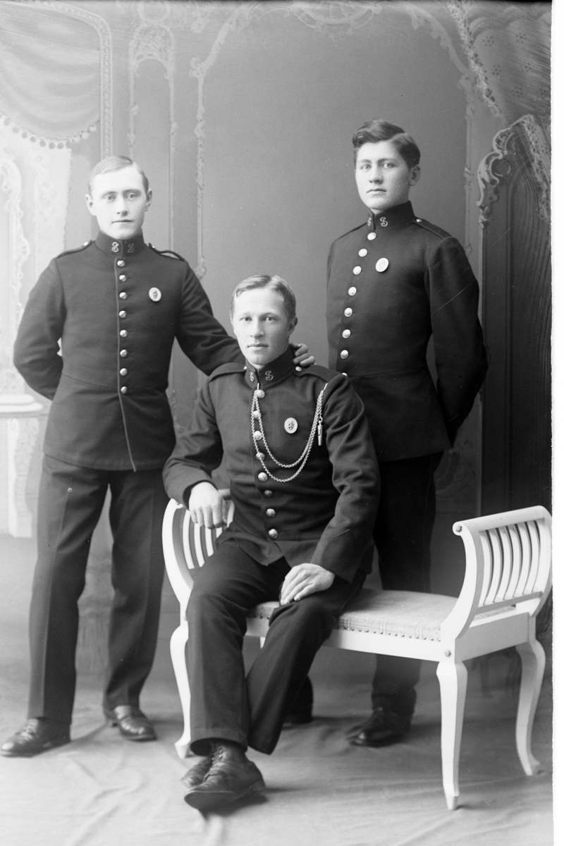 Studioportrett av tre menn i uniform.