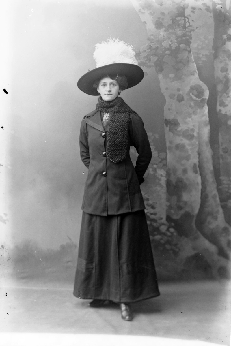 Studioportrett av en kvinne med en hatt med fjær.