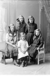 Studioportrett av fem jenter i helfigur.