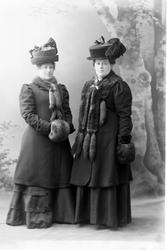 Studioportrett av to pent vinterkledde kvinner.