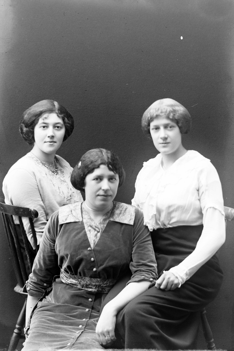Studioportrett av tre kvinner som sitter.