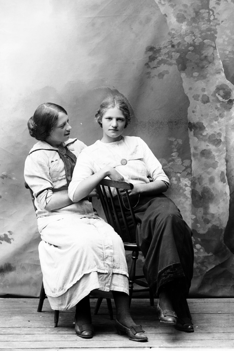 Studioportrett av to sittende kvinner.