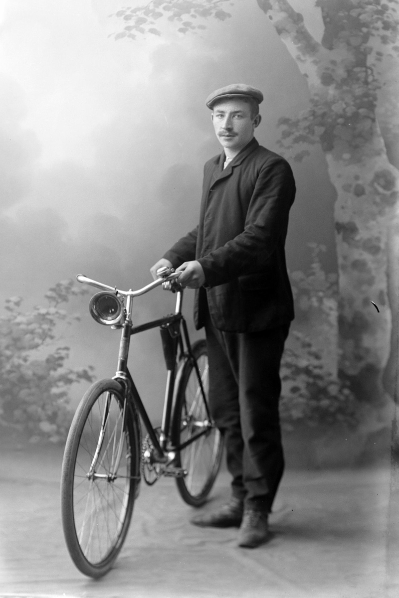 Studioportrett av en mann med sykkel i helfigur.