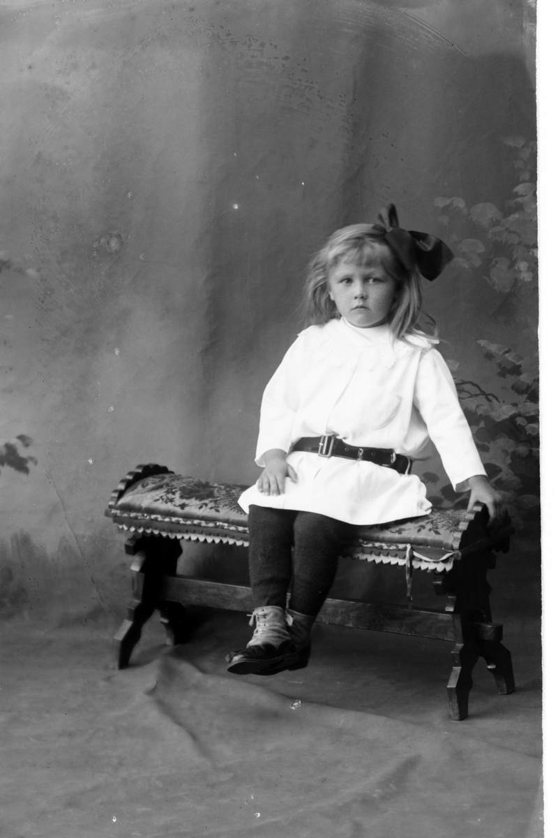 Studioportrett av en liten jente med sløyfe i håret.