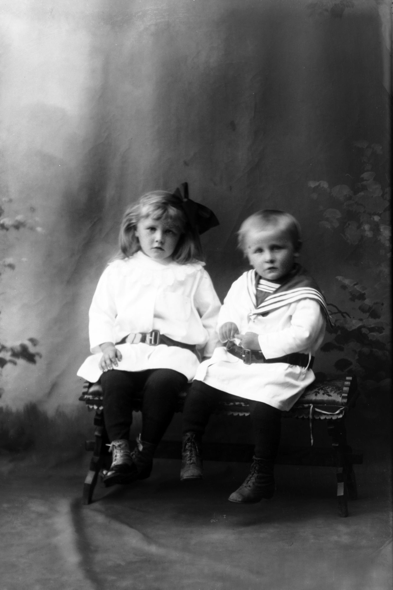 Studioportrett av to barn som sitter.