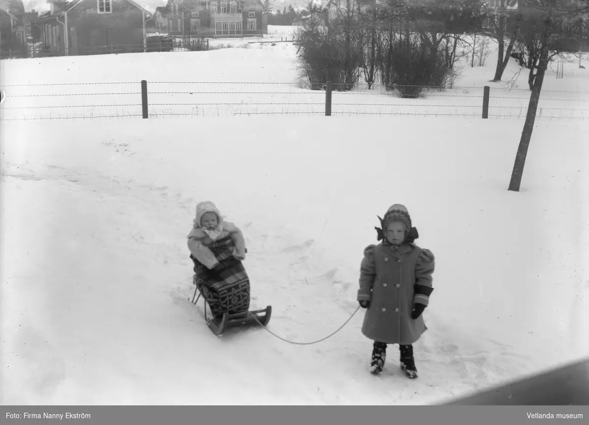 Två barn med en kälke, vy mot stationsgatan Vetlanda